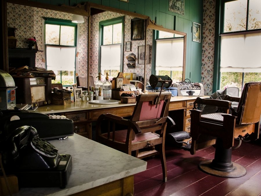 The room from the door: chairs down one wall, mirrors, daylight through the front windows.